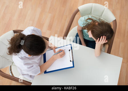 Hohe Betrachtungswinkel der Ärztin tröstend Gedrückt am Tisch sitzenden Patienten Stockfoto