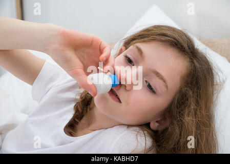 In der Nähe von Kranken Mädchen mit Nasenspray im Schlafzimmer Stockfoto