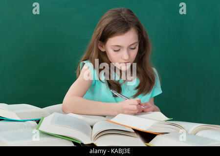 Mädchen mit vielen offenen Bücher am Schreibtisch im Klassenzimmer Stockfoto