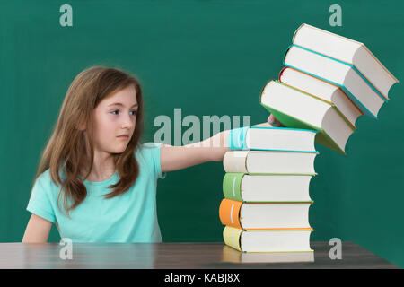 Student Am Schreibtisch, Der Stapel Bunter Bücher Im Klassenzimmer Schiebt Stockfoto