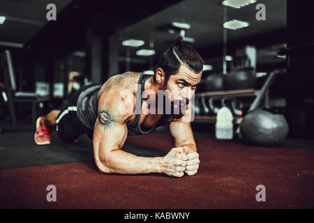 Bemuskelt junger Mann Sport Verschleiß und tun Ganzkörperstütz während des Trainings auf dem Boden im Loft Innenraum Stockfoto