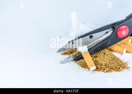 Leere Zigaretten-hülsen und Tabak mit einer Schere auf weißem Hintergrund Stockfoto