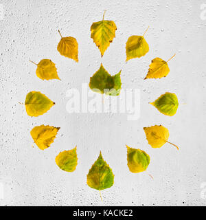 Uhr mit bunten Herbst birke Blätter auf dem nassen Glas gestapelt. One O'Clock. 1. Stockfoto