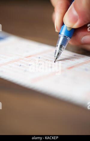 Foto der Person, die die Kennzeichnung in Lottery ticket mit Stift Stockfoto