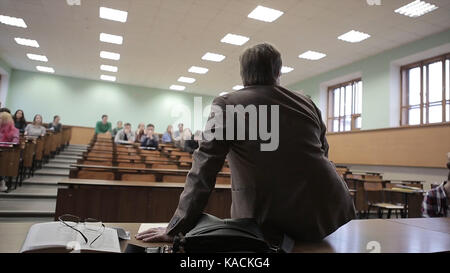 Rückansicht des Menschen präsentieren Studenten in einem Hörsaal. Ansicht von der Rückseite der Lehrer, der auf dem Tisch liegt Stockfoto