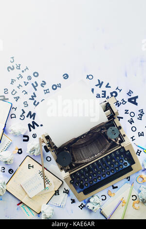 Arbeitsplatz Schriftsteller mit verstreuten Buchstaben, Briefpapier und eine Schreibmaschine. Zerknittertes Papier Kugeln mit Bleistift auf einem weißen Hintergrund Holz, Kreatives Schreiben Stockfoto