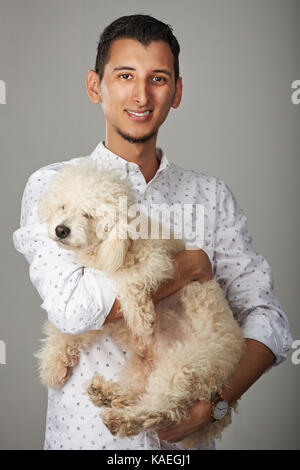 Hispanic junge lächelnde Mann mit Pudel Hund Stockfoto