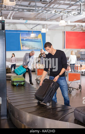 Man sammelt Gepäck am Förderband im Flughafen Stockfoto