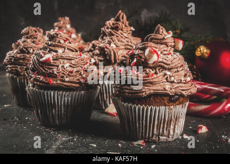 Weihnachten Süßigkeiten und Desserts, Schokolade Pfefferminz Cupcakes mit Zuckerstange Krümel, auf schwarzen Hintergrund mit Weihnachtsbaum und Kugeln, Kopie Raum Stockfoto