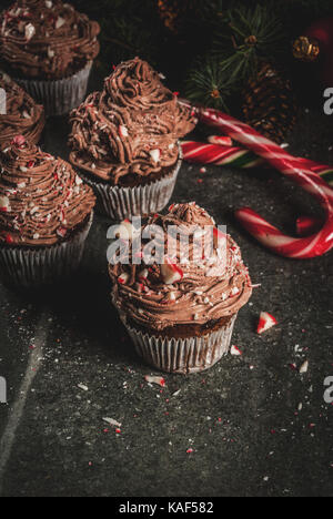 Weihnachten Süßigkeiten und Desserts, Schokolade Pfefferminz Cupcakes mit Zuckerstange Krümel, auf schwarzen Hintergrund mit Weihnachtsbaum und Kugeln, Kopie Raum Stockfoto