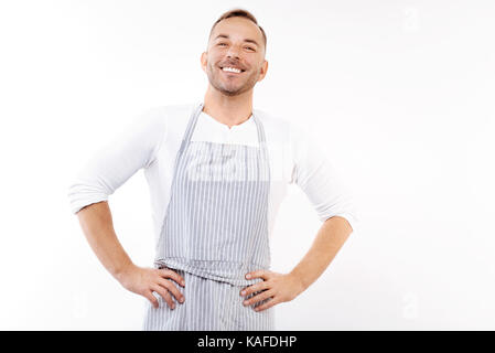 Angenehme Mann in Schürze, Hände in der Taille Stockfoto