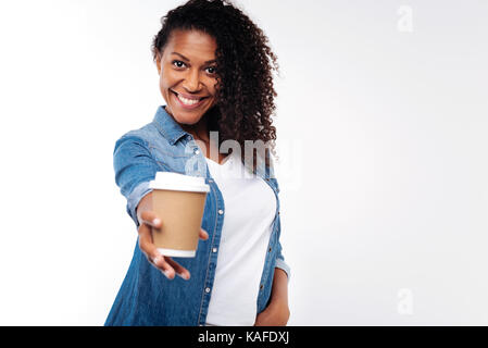 Dunkelhaarige Frau streckte Hand mit Kaffeetasse Stockfoto