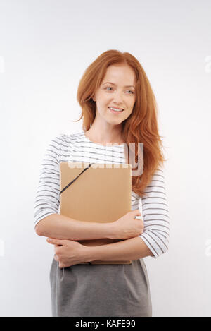 Rothaarige Frau drücken Ordner auf der Brust Stockfoto