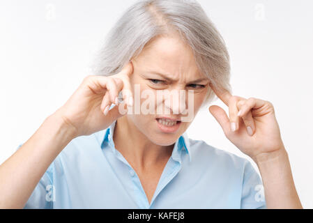 Grauhaarige Frau mit Migräne Stockfoto