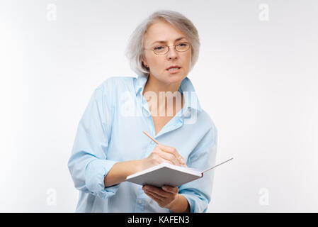 Grauhaarige Frau aufmerksam zuhören, Notizen zu machen Stockfoto