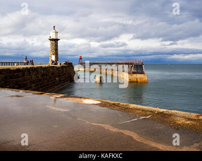 Pfütze nach dem Sommer Regen auf den Osten Pier und Leuchtturm in Whitby Yorkshire England Stockfoto