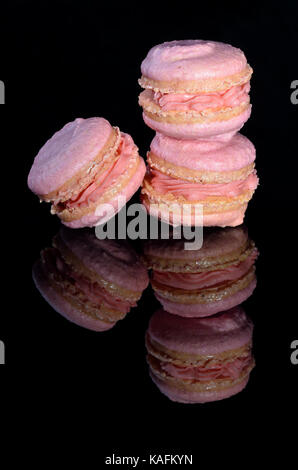 Drei rosafarbenen Macarons auf glänzenden schwarzen Hintergrund Stockfoto