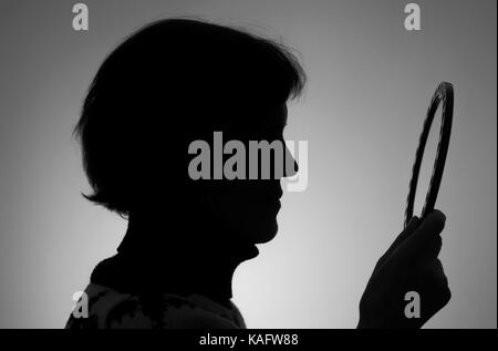 Schwarz-weiß-Porträt (Umriss) der reifen Frau im Spiegel zu betrachten Stockfoto