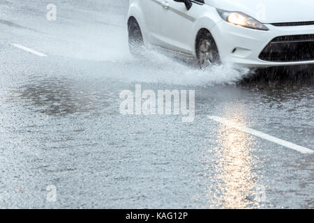 Auto fahren durch Pfützen. Regenwasser Sprühen aus der Räder. Stockfoto