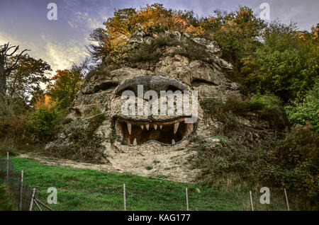 Blick auf geschnitzt Natur Skulptur Kopf Lion am Fels am Rand Straße im Herbst Abend Stockfoto