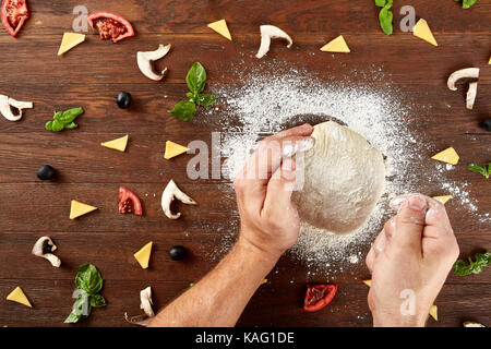 Hände kneten Sie den Teig für Pizza backen Stockfoto