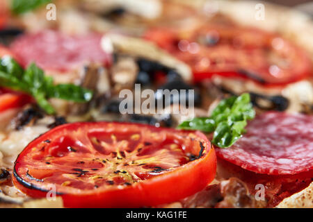 Nahaufnahme von Pizza mit Salami, Tomaten und Oliven Stockfoto