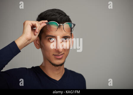 Junger Mann mit Brille auf die Stirn auf grauem Hintergrund Stockfoto