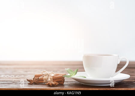 Weißes Porzellan Tasse Tee mit Zimtstangen, Zitrone, Minze und Teesieb Stockfoto