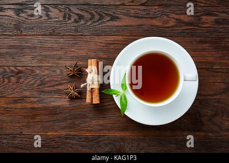 Weißes Porzellan Tasse Tee mit Zimtstangen, Zitrone, Minze und Teesieb Stockfoto