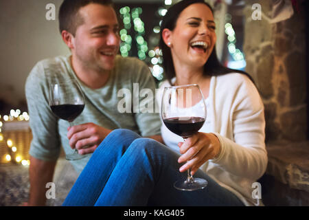 Paar vor einem Kamin zu sitzen, Wein trinken. Stockfoto
