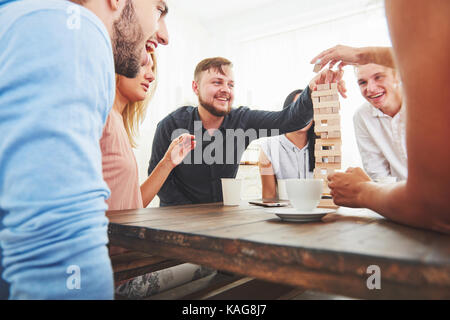 Gruppe der kreativen Freunde an den hölzernen Tisch sitzen. Menschen Spaß beim spielen brettspiel Stockfoto