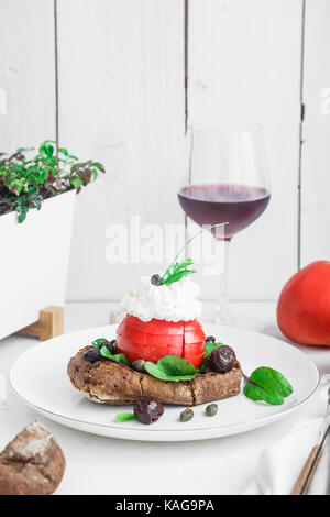 Gerste Zwieback genannt Dakos, gekrönt mit Feta Käse, Tomaten würfeln, Olivenöl und Oregano, typisch griechische Platte mit Wein serviert Stockfoto