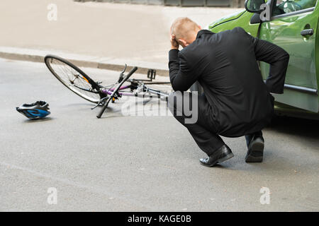 Traurig männliche Fahrer nach der Kollision mit dem Fahrrad auf der Straße Stockfoto