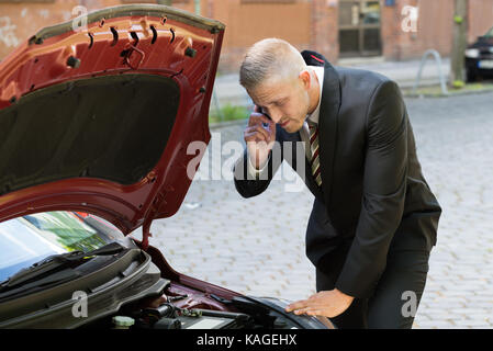 Porträt eines jungen Mannes Anrufen auf Handys für Auto Service Stockfoto