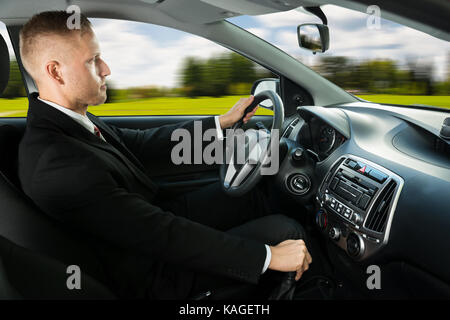 Junger Mann Gangwechsel während der Fahrt ein Auto Stockfoto