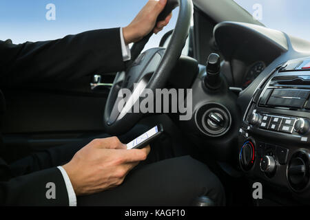 Nahaufnahme von einem Mann mit Handy während der Fahrt Auto Stockfoto