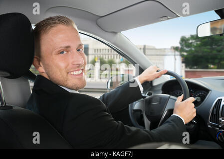 Portrait Of Happy Geschäftsmann, der in seinem Auto Stockfoto