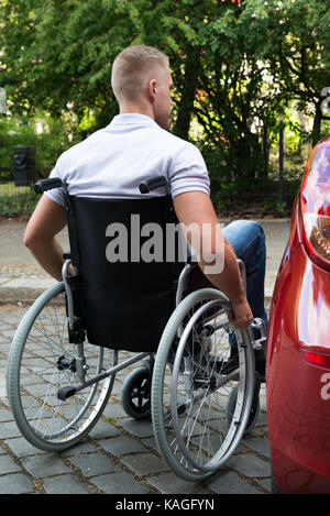 Ansicht der Rückseite ein junger Mann im Rollstuhl Neben seinem Auto Stockfoto