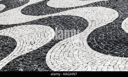 Typisch portugiesische Kopfsteinpflaster Muster aus schwarzen und weißen Wellen. Lissabon, Portugal Stockfoto