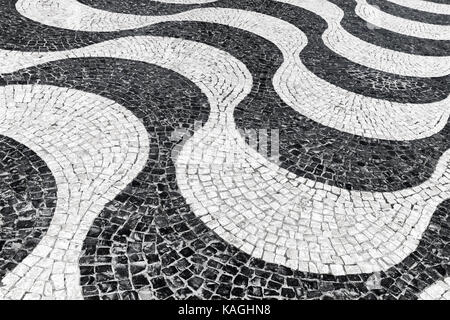 Typisch portugiesische Cobblestone handgefertigte Pflaster Muster aus schwarzen und weißen Wellen. Lissabon, Portugal Stockfoto