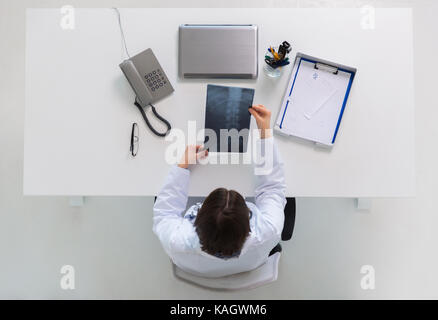 Doktor mit Wirbelsäule x-ray an Tisch sitzen Stockfoto