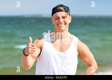 Lächelnder Mann mit Daumen hoch auf Sommer Strand Stockfoto