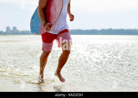 Glückliche junge Mann mit skimboard auf Sommer Strand Stockfoto