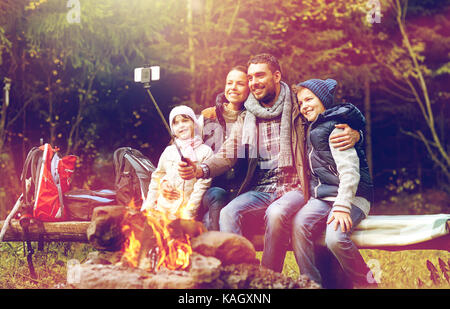 Familie mit Smartphone unter Selfie nahe am Lagerfeuer Stockfoto