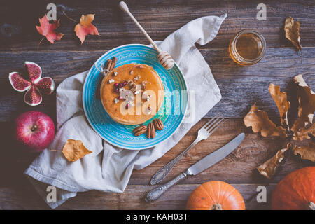 Pumkin Pfannkuchen auf einer blauen Platte auf hölzernen Hintergrund serviert mit Pekannuss und Honig. Herbst essen Still Life Stockfoto