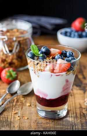 Joghurt mit Müsli, Blaubeeren und strawberies in Glas auf Holz- Tabelle. Gesunde Snack, Ernährung, Reinigung low carb Diät Lebensmittel Stockfoto