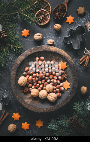 Weihnachten Winter Dekorationen, Walnüsse, Haselnüsse, christmas tree branch, Gewürze, Ausstechformen und Orange Stars noch leben. top Aussicht, getönten Bild Stockfoto