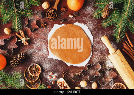 Lebkuchen Cookie Teig ausgerollt auf dem Tisch mit Weihnachten und neues Jahr Dekorationen. Ausstechformen, Tannenbaum, Tannenzapfen, Gewürze, Mehl, Nüsse ein Stockfoto