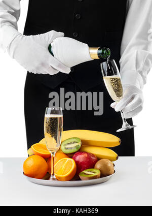 Kellner gießt in Glas Champagner auf weißem Hintergrund. Romantisches Abendessen Stockfoto