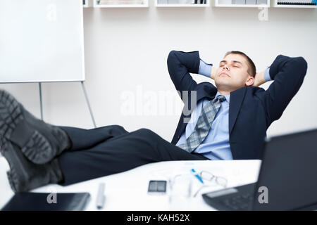 Müde, Geschäftsmann, schlafen auf Stuhl im Büro mit seinen Beinen auf dem Tisch Stockfoto